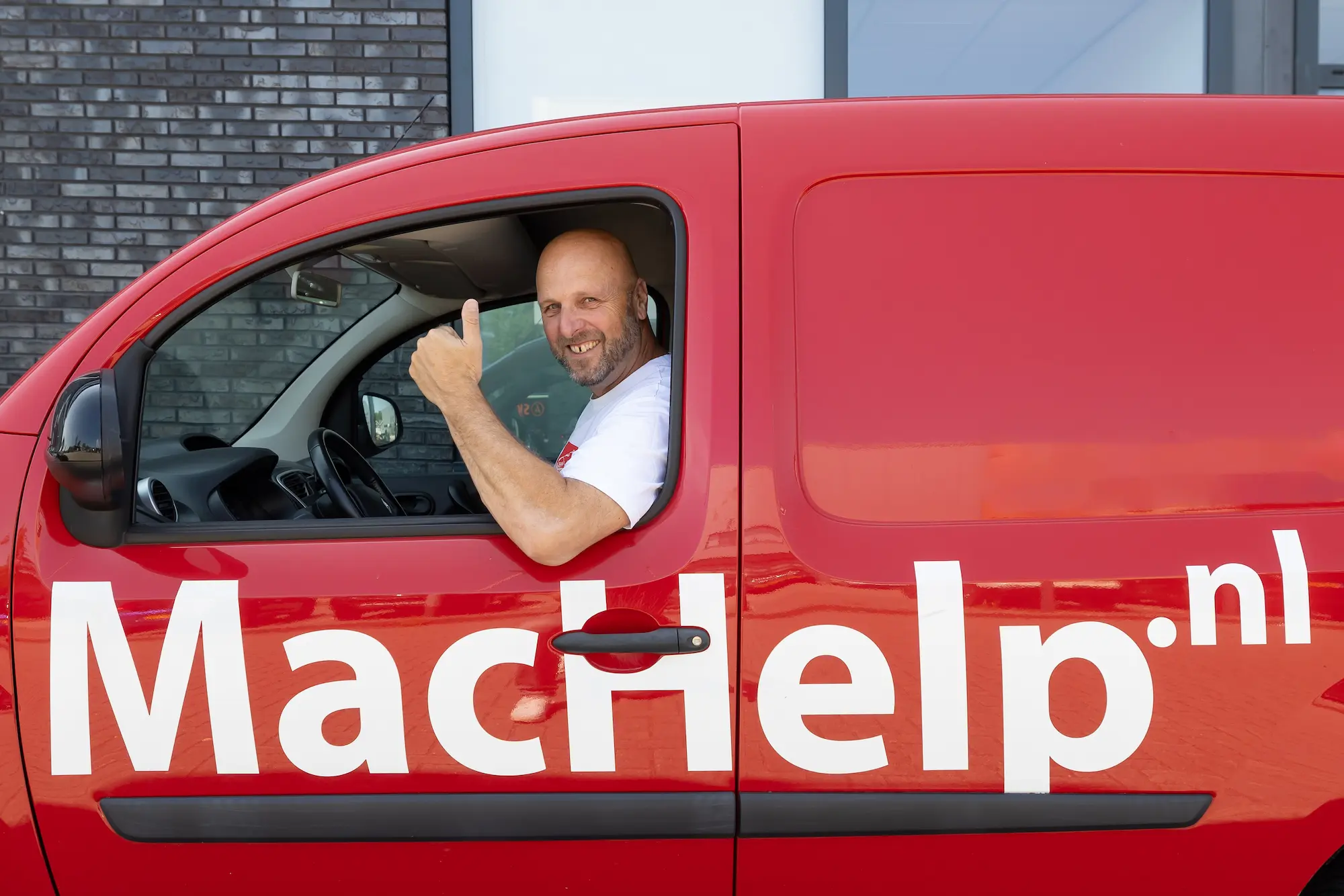 Dennis van MacHelp in de bedrijfsbus met MacHelp.nl op de zijkant